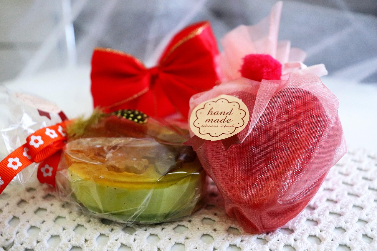handmade soap, artisanal gift, gift wrap, pink mesh, crochet background, bath gift, handmade label, soap packaging, craft fair, diy gift, festive soap, heart soap, clear wrap, red bow, skincare gift, creative packaging, handmade design, soap art, natural product, rustic gift, holiday soap, soap favor, body care, delicate wrapping, cozy decor